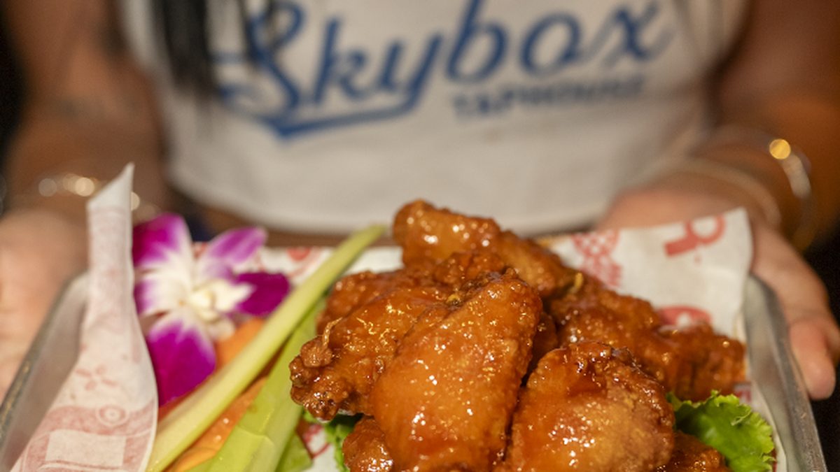 Skybox Taphouse server holding a tray of jumbo Hawaiian BBQ wings in Waikiki